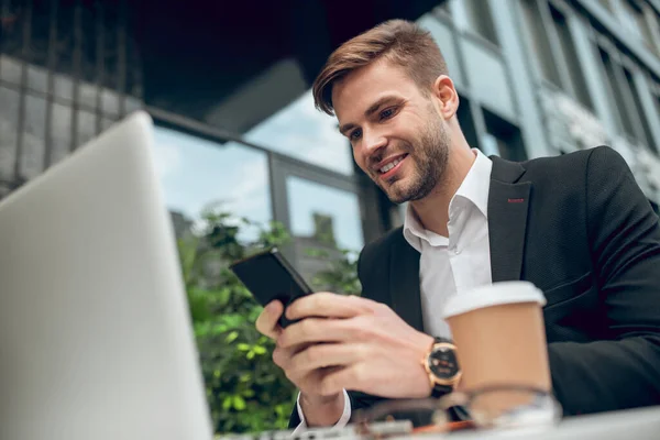 Snygg ung affärsman som dricker kaffe och messar — Stockfoto