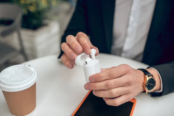 Primer plano de las manos del hombre sosteniendo auriculares inalámbricos — Foto de Stock