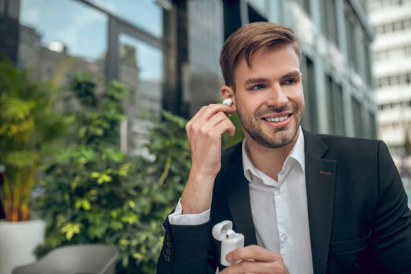 Knappe man met een draadloze hoofdtelefoon en een tevreden blik — Stockfoto