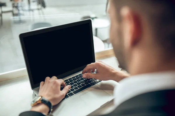 Közelkép fiatal üzletemberről, aki a laptopon dolgozik egy kávézóban. — Stock Fotó