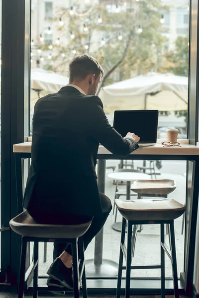 Fiatal üzletember ül egy kávézóban, és dolgozik a laptop — Stock Fotó
