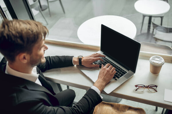 Young businessman working on the laptop in a cafe and looking involved