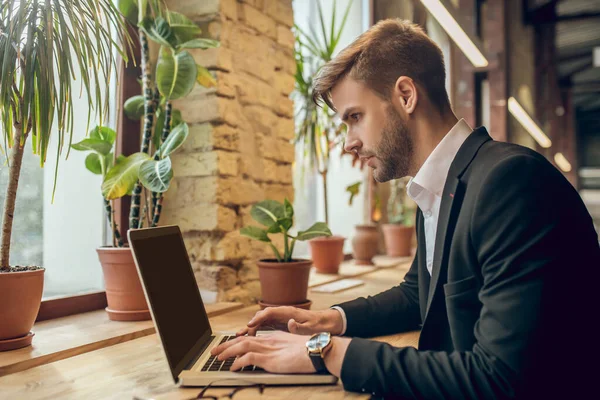 Fiatal üzletember dolgozik a laptop egy kávézóban, és úgy néz ki, koncentrált — Stock Fotó