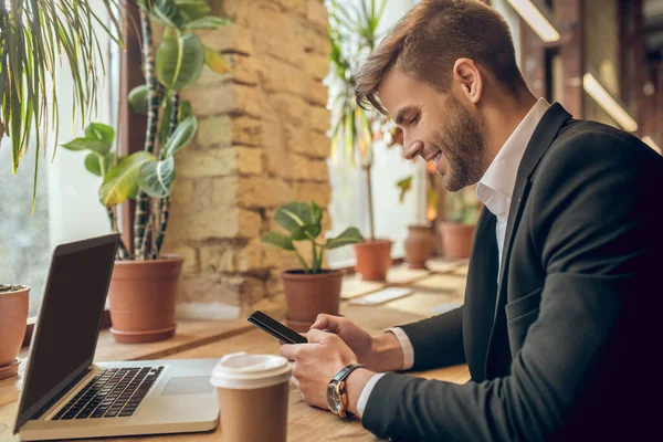 Joven empresario sosteniendo un teléfono inteligente y mensajes de texto — Foto de Stock