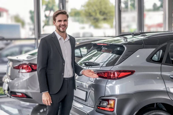 Bearded male pointing at car boot in the showroom