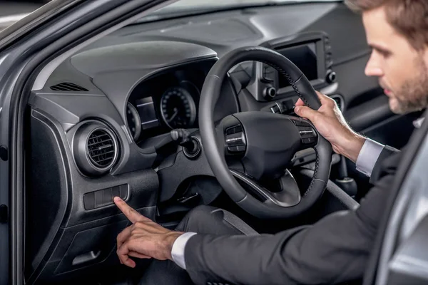 Young male holding steering wheel, pressing control buttons — Stock Photo, Image