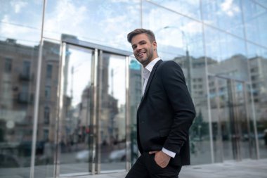 Siyah takım elbiseli zarif genç adam güzelce gülümsüyor.