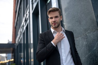 Siyah takım elbiseli, kendine güvenen genç bir adam.