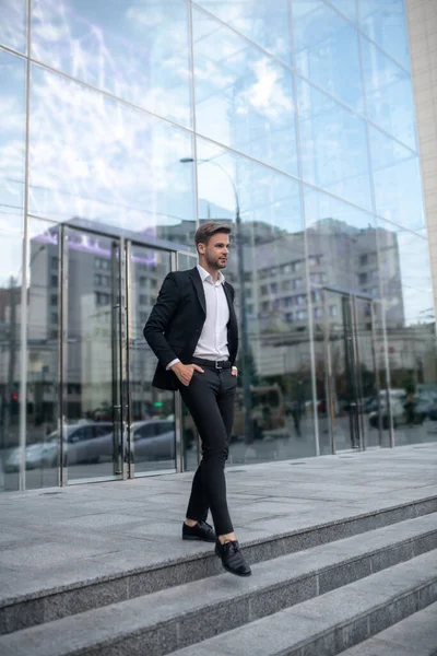 Jovem elegante em um terno preto nos degraus — Fotografia de Stock