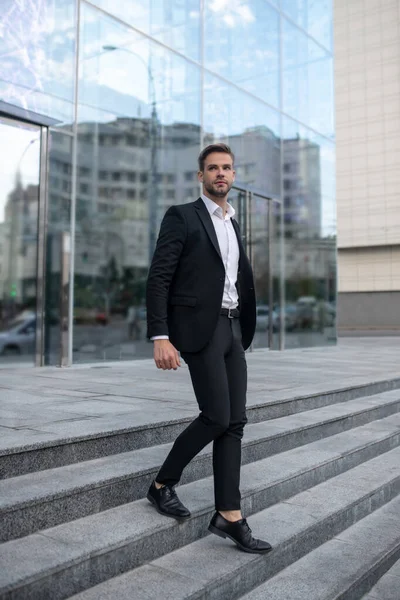 Stylish young man in a black suit on the steps — Stock Photo, Image