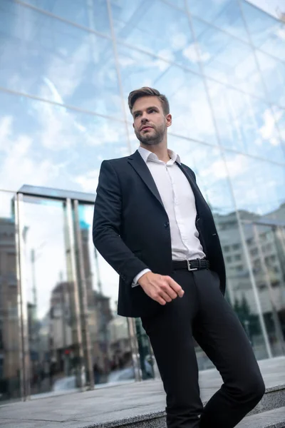 Elegante jongeman in een zwart pak op stedelijke achtergrond — Stockfoto