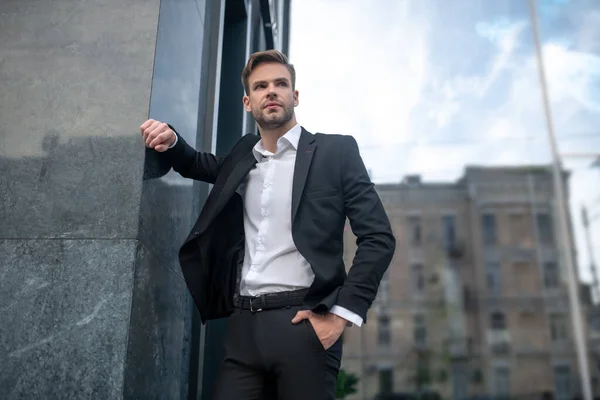 Jovem elegante em um terno preto posando perto da parede — Fotografia de Stock