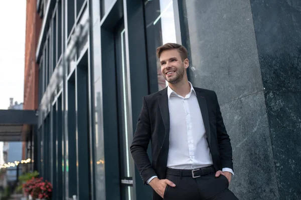 Jovem elegante em um terno preto sorrindo e se sentindo bem. — Fotografia de Stock