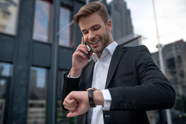 Mladý muž v černém obleku mluví po telefonu a domlouvá si schůzku — Stock fotografie
