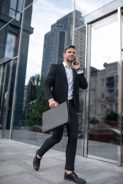 Ung man med portfölj pratar i telefon och går till jobbet — Stockfoto