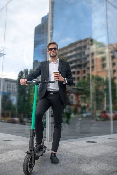 Confident businessman in sunglasses with the scooter in the street — Stock Photo, Image
