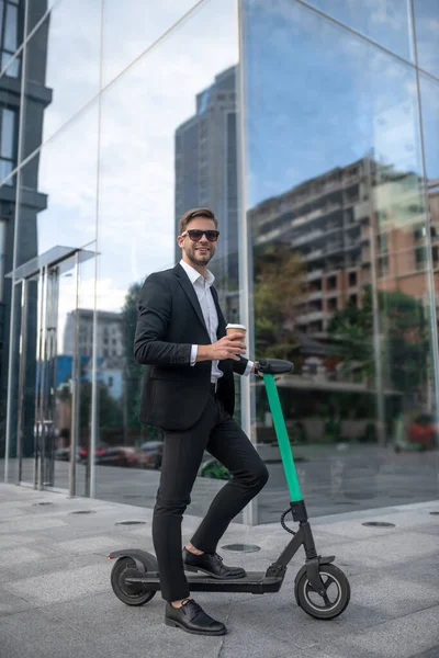 Young businessman in sunglasses with the scooter having coffee — Stock Photo, Image