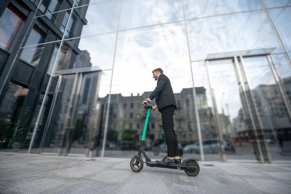 Homem em uma scooter perto de um edifício alto — Fotografia de Stock