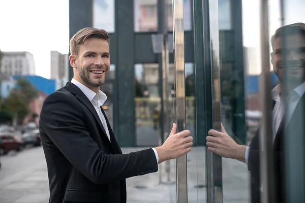 Elegante mannelijke zakenman die het businesscentrum binnenkomt en glimlacht — Stockfoto