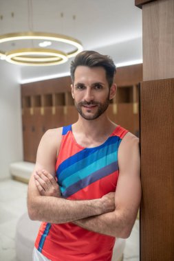 Parlak tişörtlü genç adam pozitif görünüyor.