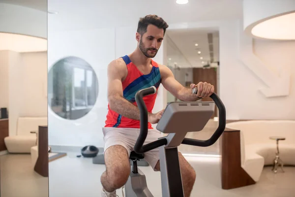 Sportieve man in heldere tshirt oefenen op een fitnessapparaat — Stockfoto