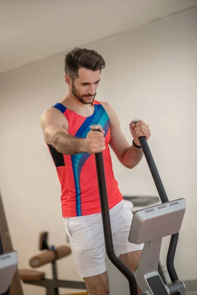 Joven hombre moreno haciendo ejercicio en el gimnasio y buscando determinado — Foto de Stock