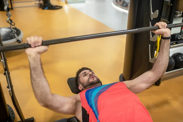 Jonge donkerharige man werkt met gewichten in de sportschool — Stockfoto