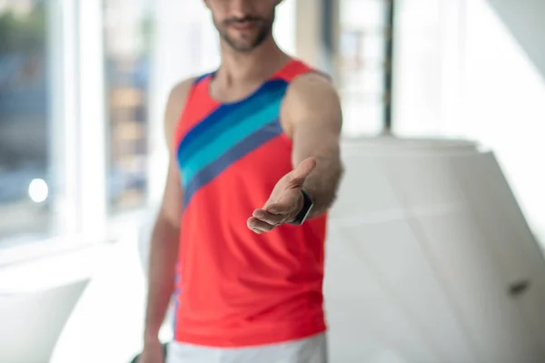 Спортивный человек в яркой футболке протягивает руку — стоковое фото
