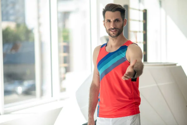 Sporty man in bright tshirt standing with an outstretched arm — Stock Photo, Image