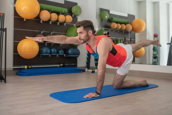 Barbudo joven macho practicando ejercicio de perro pájaro — Foto de Stock