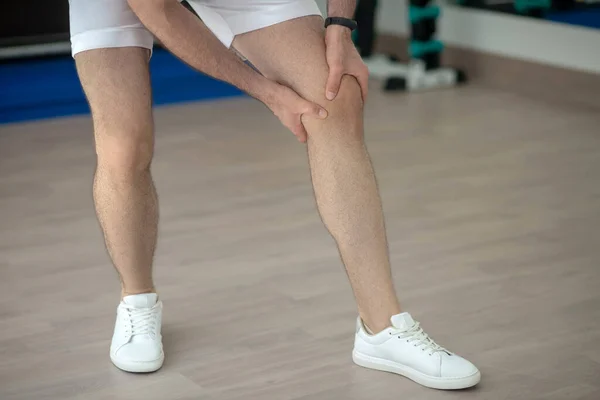 Κοντινό πλάνο των αρσενικών χεριών μασάζ επώδυνο γόνατο στο γυμναστήριο — Φωτογραφία Αρχείου