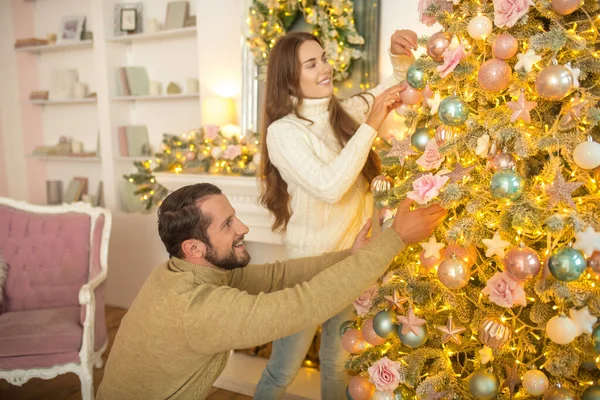 Young happy couple decorating christmas tree together — Stock Photo, Image