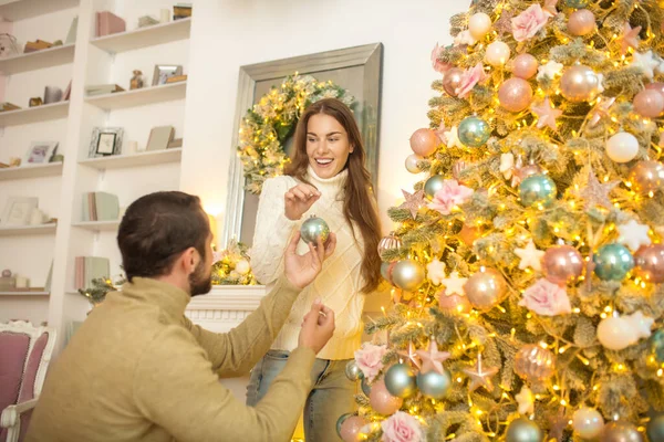 Joven pareja feliz poniendo bals de Navidad en un árbol de Navidad — Foto de Stock