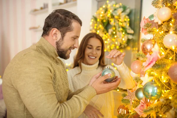 Jeune couple heureux mettant des boules de Noël sur un arbre de Noël — Photo