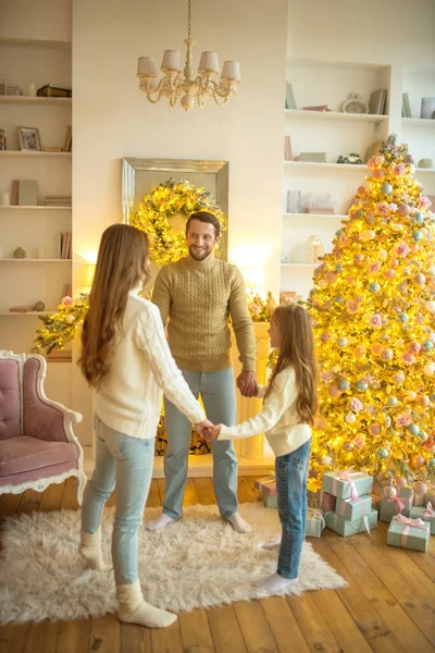 Jeune famille heureuse tenant la main près de l'arbre de Noël — Photo