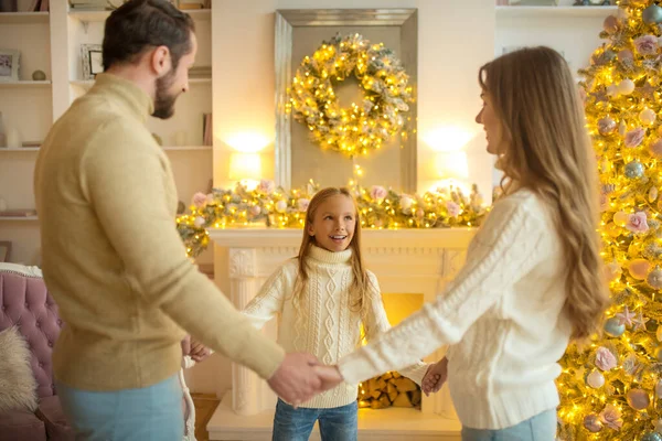 Happy family standing near christmas tree and holding hands — Stock Photo, Image