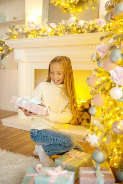 Blonde cute girl looking busy looking at the christmas presents — Stock Photo, Image