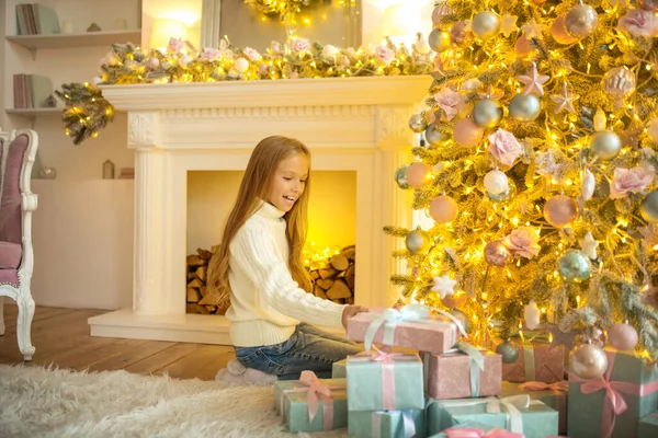 Szőke csinos lány néz elfoglalt nézi a karácsonyi ajándékokat — Stock Fotó