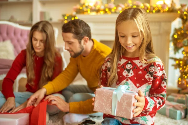 Jong gezin verpakking kerstcadeaus en op zoek betrokken — Stockfoto