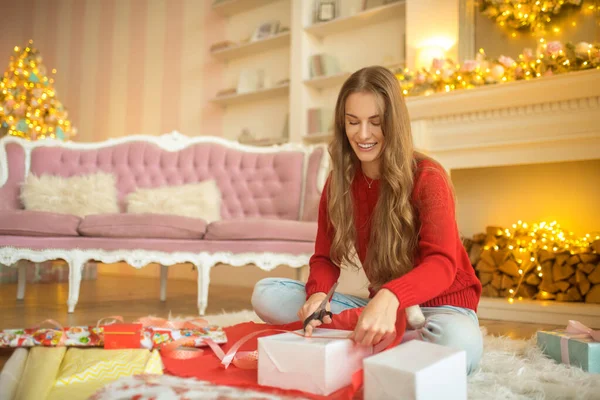 Ciemnowłosa młoda kobieta pakuje prezenty świąteczne i wygląda na zajętą — Zdjęcie stockowe
