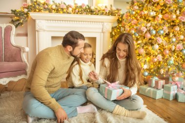 Genç aile Noel hediyelerini açtığı için mutlu.