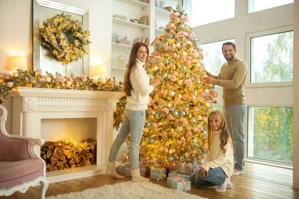 Χαριτωμένη νεαρή οικογένεια διακόσμηση χριστουγεννιάτικο δέντρο στο σπίτι — Φωτογραφία Αρχείου