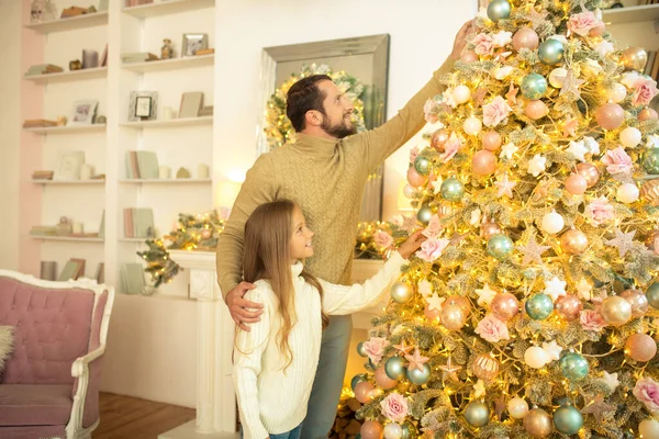 Father and daughter decorating christmas tree and looking involved — Stock Photo, Image