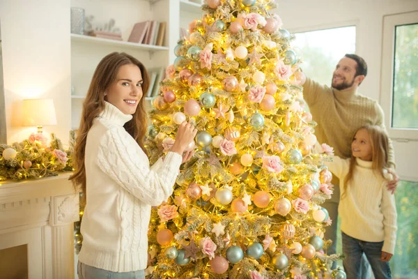 Young parents and their daughter decorating christmas tree — Stock Photo, Image