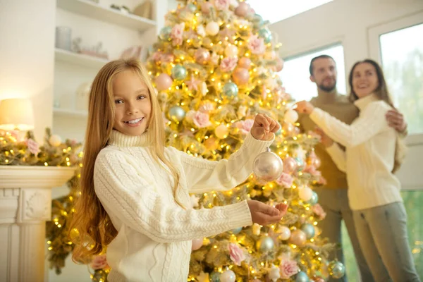 Jolie fille aux cheveux blonds décorant le nouvel arbre de l'année avec ses parents — Photo