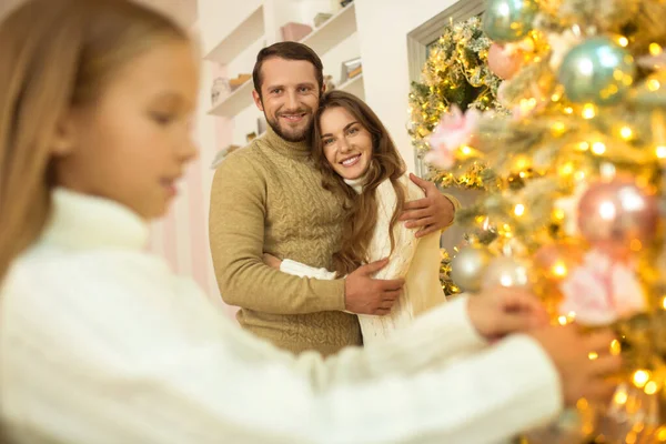 Papa met des couilles sur l'arbre de Noël pendant que sa femme et sa fille le regardent — Photo