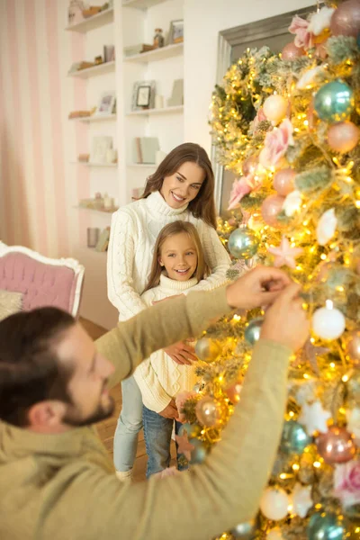 Papa met des couilles sur l'arbre de Noël pendant que sa femme et sa fille le regardent — Photo