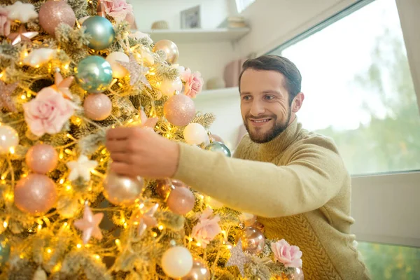 Bärtiger schöner Mann schmückt Neujahrsbaum — Stockfoto