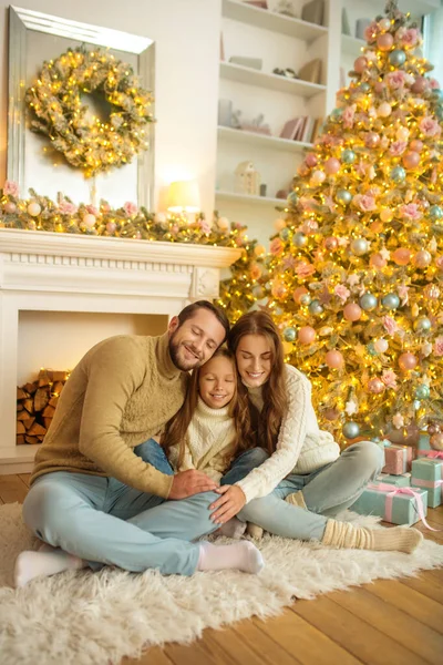 Keluarga yang tersenyum gembira duduk di lantai dekat pohon natal — Stok Foto
