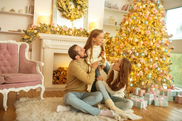 Young family feeeling happy sitting near the new year tree — Stock Photo, Image